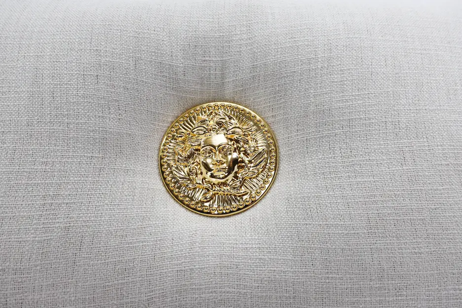 Elegantes Kissen aus rustikalem Leinen mit einer goldenen Applikation, die an den Stil von Versace erinnert